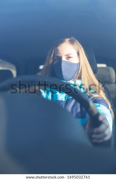 Woman wearing surgical mask in the car, for\
corona virus or Covid-19\
protection.