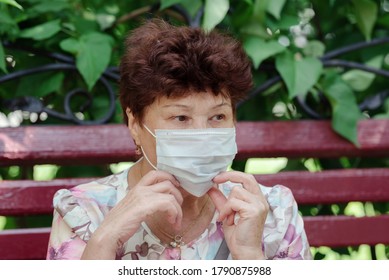 Woman Wearing Surgical Mask Epidemic Prevention Covering Face. Senior Woman In Late 60s Using Mask Looking To Camera.