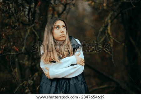 
Woman Wearing a Sweater and a Vest Feeling Cold. Lady feeling afraid and chill in the woods during autumn season
