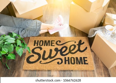 Woman Wearing Sweats Relaxing Near Home Sweet Home Welcome Mat, Moving Boxes and Plant.