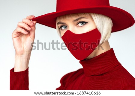 Woman wearing trendy fashion outfit during quarantine  of coronavirus outbreak. Total red look including protective stylish handmade face mask
