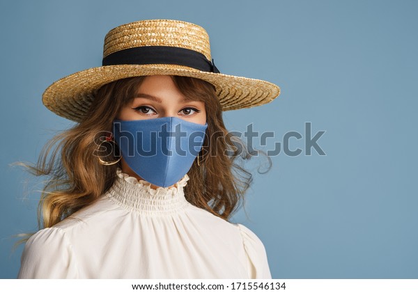 コロナウイルス感染の検疫中に流行の春 夏のファッション服を着た女性 モデルは 防護用のスタイリッシュな手作りのフェイスマスク 麦わら帽子 白いブラウス イヤリングを身に付けます コピー 空白 の写真素材 今すぐ編集
