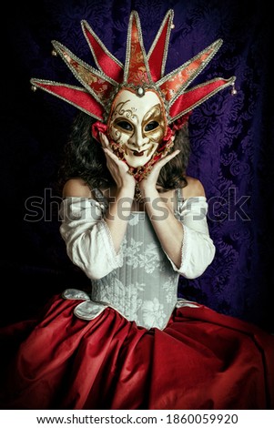 A woman wearing a Venetian carnival mask with a corset and red skirt