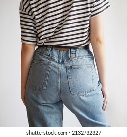 Woman Wearing Vintage Mom Jeans And Striped T-shirt On White Background.