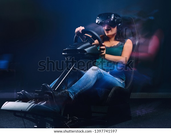 Woman wearing VR headset\
having fun while driving on car racing simulator cockpit with seat\
and wheel.
