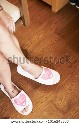 Woman wearing white bathroom slippers sitting on the chair with wooden floor