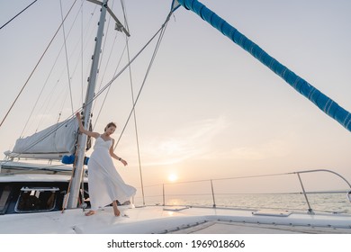 Woman Wearing White Dress Relax On Sailing Yacht, Romantic Sunset.