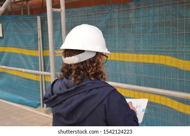 Woman Wearing White Hard Hat Back To Camera At Construction Site