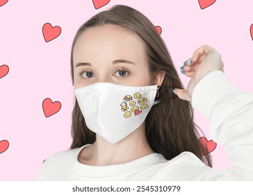 Woman wearing a white mask with emojis, hearts in the background. Mask with emojis, woman adjusting mask, hearts pattern. White mask, emojis, hearts. - Powered by Shutterstock