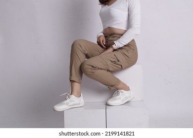 Woman Wearing White Shirt And Beige Pants Taking A Photo In The Studio