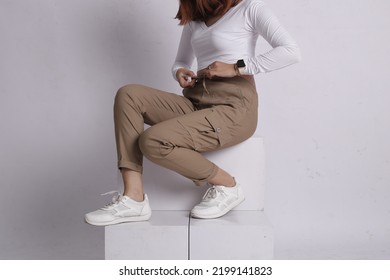 Woman Wearing White Shirt And Beige Pants Taking A Photo In The Studio