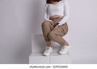 Woman Wearing White Shirt And Beige Pants Taking A Photo In The Studio