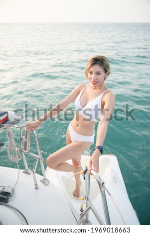 Woman wearing white swimsuit relax on sailing yacht, romantic sunset.