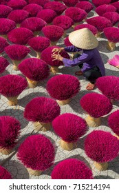 Woman wearning conical hat is drying sticks of incense at yard at Tay Ninh province, Vietnam Stock Photo