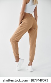 Woman Wears Khaki Pants. Fit Girl Is Standing In Beige Joggers