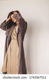 Woman Wears Long Silk Kimono, Silk Loungewear And Grey Coat. Handmade Robe. Details Of Minimalist Look. Woman Dressed In Fashionable Beige Wrap Around Midi Dress. Street Fashion. Girl Fix Her Hair.