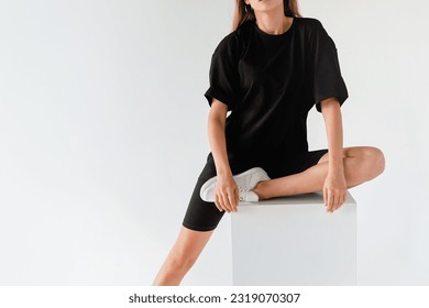 woman wears oversize black shirt and black shirt. dark streetwear outfit young girl