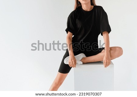 woman wears oversize black shirt and black shirt. dark streetwear outfit young girl