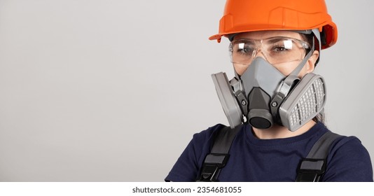 A woman wears a protective respirator with dust and gas filters on a white background.