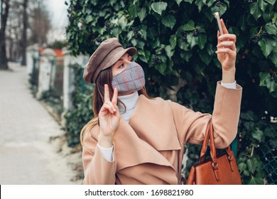 Woman Wears Reusable Hand Made Mask Outdoors During Coronavirus Covid-19 Pandemic. Girl Taking Selfie On Phone On Empty Street. Stay Safe. Spring Fashion