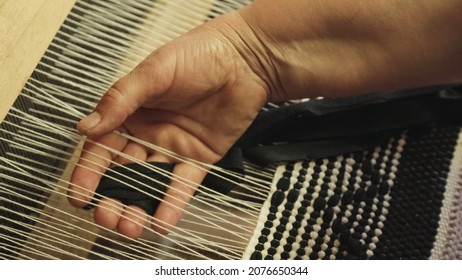 Woman weaver hand working with old weaving tool. Process of fabric production. Textile industry concept. Close up of weaving machine in action.