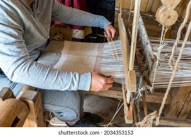 A Woman Weaver Makes Fabric On An Old Hand Loom. Handmade Woven Products.