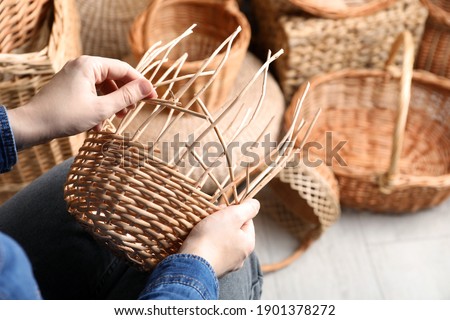 Woman weaving wicker basket indoors, closeup view