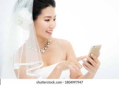 A woman in wedding dress has a smartphone - Powered by Shutterstock