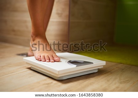 Woman weighing herself on weight scale in bathroom