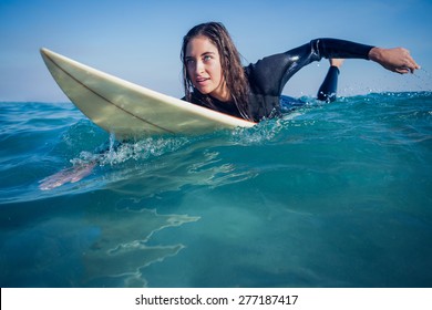 woman in wetsuit with a surfboard on a sunny day at the beach - Powered by Shutterstock