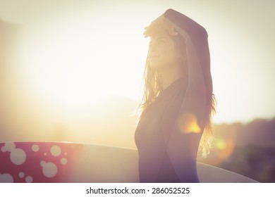 woman in wetsuit with a surfboard on a sunny day on the beach - Powered by Shutterstock