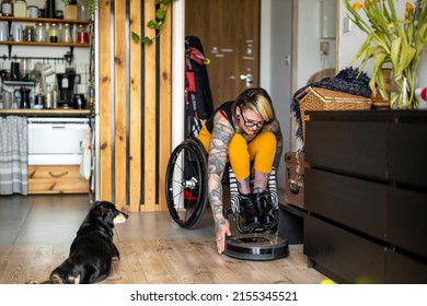 Woman in wheelchair adjusting smart robot cleaner at home
