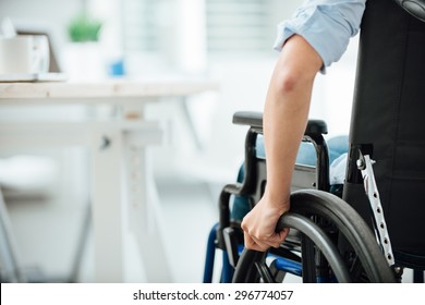 Woman in wheelchair next to an office desk, hand close up, unrecognizable person