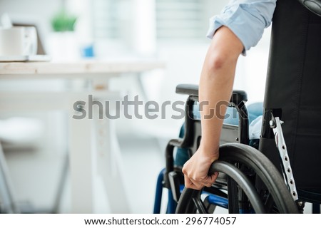 Woman in wheelchair next to an office desk, hand close up, unrecognizable person