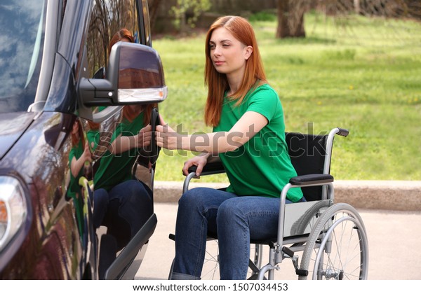 Woman in\
wheelchair opening door of her van\
outdoors