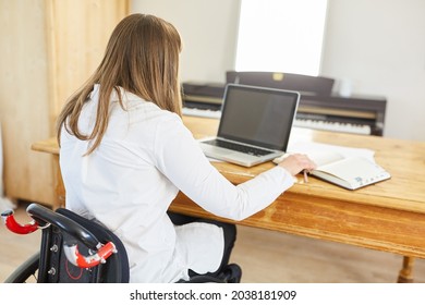 Woman In A Wheelchair With Paraplegia Works On The Laptop Computer Online In The Home Office