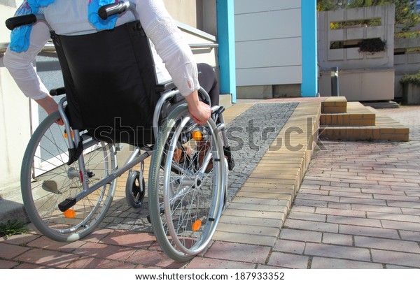 Woman in a wheelchair using\
a ramp