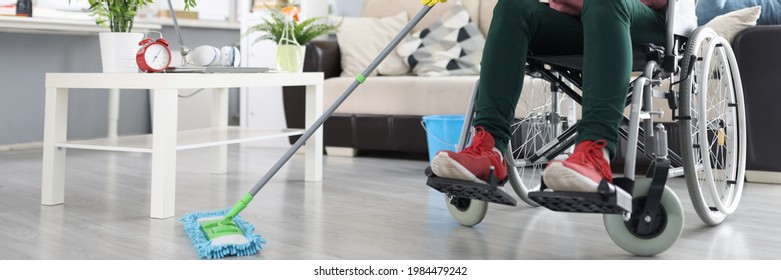 Woman in wheelchair washes the floor with mop - Powered by Shutterstock