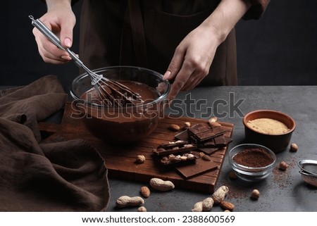 Woman with whisk mixing delicious chocolate cream at table, closeup