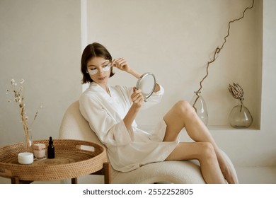 Woman in white bathrobe adjusting her eye patch while resting in shaped chair - Powered by Shutterstock