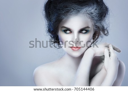 Woman with white body-art in creative image of winter, snow queen, or another sad or evil character