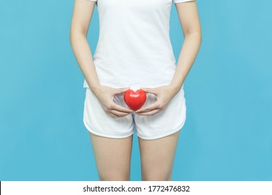 woman in white clothes holding red heart put on the genitalia area, pain or Itching urinary Health-care concept on blue background