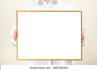 Woman In White Clothes Shows An Empty Mockup Frame. Researcher Or Doctor Holds A Golden Mockup Frame. Woman Holding Blank White Frame.