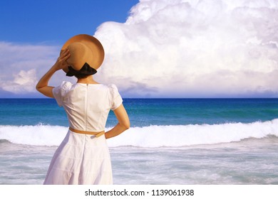 The woman in a white dress looking at the beautiful tropical sea. Summer, travel, vacation, holiday concept. 
