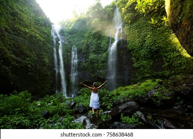 Woman in white dress at the Sekumpul waterfalls in jungles on Bali island, Indonesia