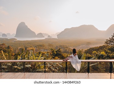 Woman with the white dress sit and see the mountain in early morning at the Sametnangshe Island viewpoint, Phang-Nga, Thailand.