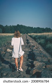Woman in white dress walking along the stone pier at sunny hot day. High quality photo