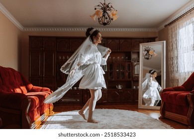 A woman in a white dress is walking in a room with a red couch. She is wearing a veil and is looking at her reflection in a mirror. The room has a warm and cozy atmosphere, with a red couch - Powered by Shutterstock