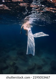 Woman with white fins swimming in deep blue ocean - Shutterstock ID 2195053467