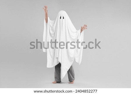 Woman in white ghost costume on light grey background. Halloween celebration